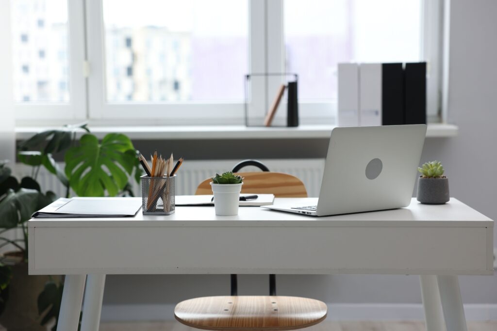 Stylish workplace with laptop and stationery on white table in office